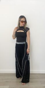 Donna indossa pantalone nero con gamba in pizzo, tasche cargo laterali, dettagli in denim e fondo regolabile.