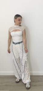 Donna indossa pantalone nero con gamba in pizzo, tasche cargo laterali, dettagli in denim e fondo regolabile.