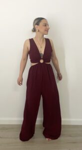 Jumpsuit color bordeaux con scollo a V, cut-out rotondo sul davanti, fianchi elasticizzati e gamba palazzo. Indossata da modella alta 1,60 m, taglia S