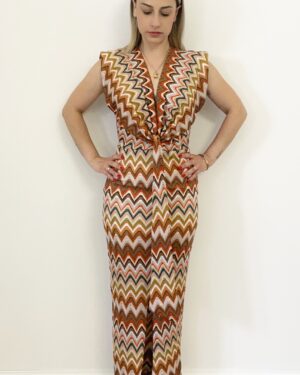 Donna indossa abito lungo con fantasia zigzag multicolor, scollo a V e nodo in vita