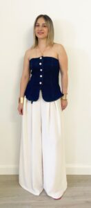 Donna indossa il pantalone “Ghiaccio”, modello palazzo color chiaro con pinces e cintura nera