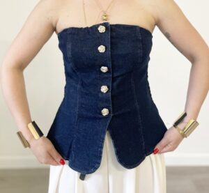 Donna indossa il top “Troppa Fascia in Denim” con bottoni dorati e retro elasticizzato