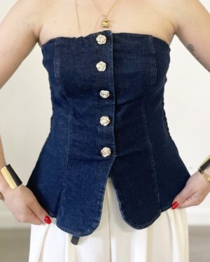 Donna indossa il top “Troppa Fascia in Denim” con bottoni dorati e retro elasticizzato