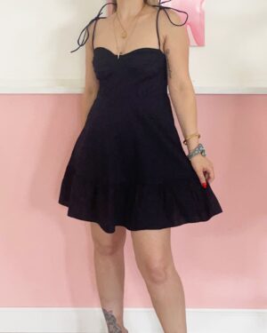 Mini abito blu scuro con bretelle a fiocco e taglio svasato indossato da modella.