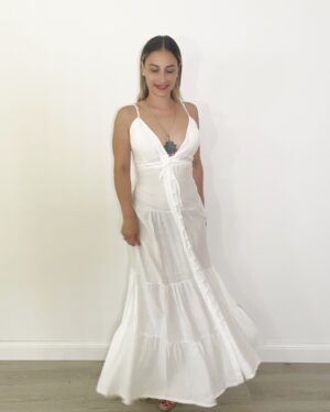 Abito lungo bianco con spalline sottili, scollo a V profondo con coppe, bottoni veri frontali e balze leggere.