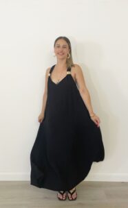 Abito lungo nero over con spalline larghe, dettagli oro sulle bretelle e schiena intrecciata.
