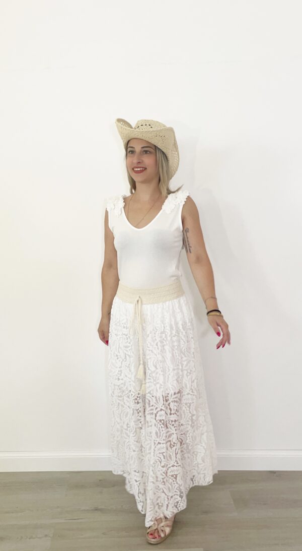Pantaloni ampi in pizzo beige panna con elastico in vita e fodera interna, indossati con canotta bianca e cappello di paglia.
