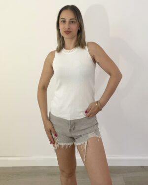 Canotta in filo bianca con girocollo decorato di perle bianche e argento, indossata da modella con shorts grigi.”