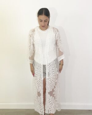 “Kimono lungo in pizzo bianco con motivo floreale indossato da modella su top bianco e shorts, vista frontale.”