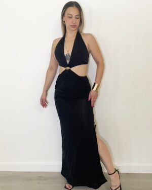 Donna indossa abito lungo nero con cut-out laterali, scollo allacciato dietro il collo e dettaglio gioiello centrale.