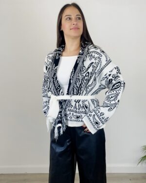 Cardigan azteco bianco con fantasia nera, indossato con cintura bianca e pantalone nero palazzo.
